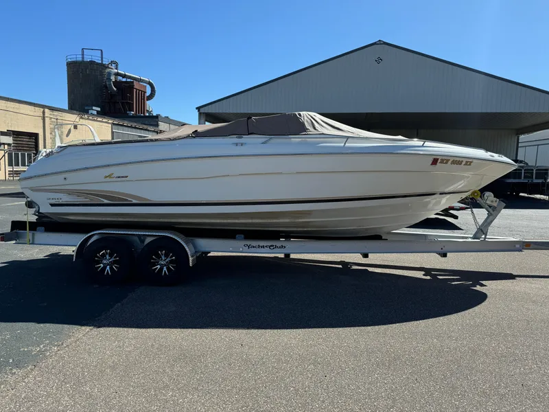 Slide: The Image of 1996 Sea Ray 260 Bow Rider on trailer, parked outdoors near industrial buildings. - 9