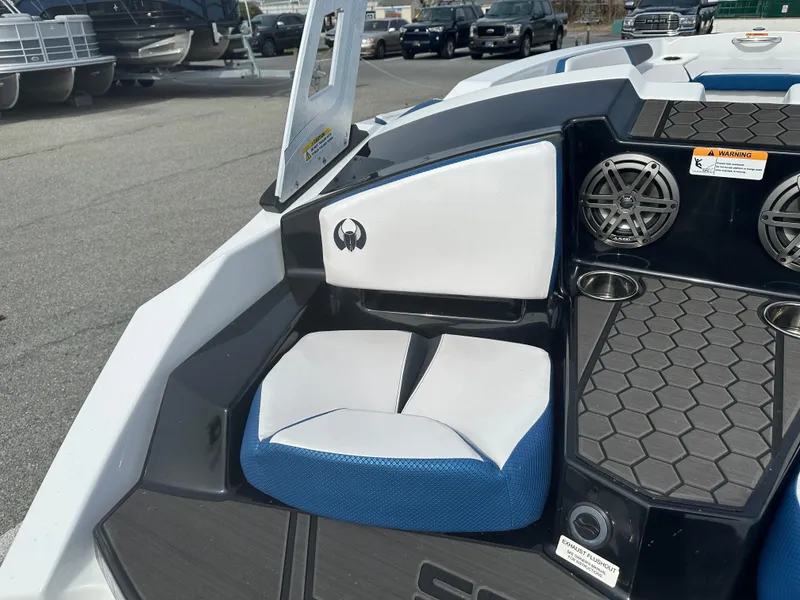 Slide: The Image of 2023 Scarab 165ID boat interior with white and blue seating, speakers, and cup holders. - 11