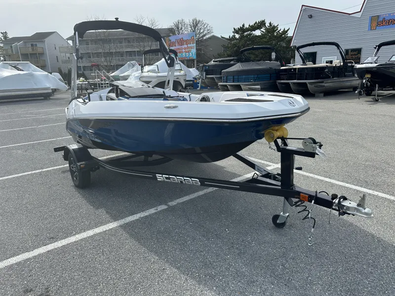 Slide: The Image of 2023 Scarab 165ID boat on a trailer in a parking lot. - 2