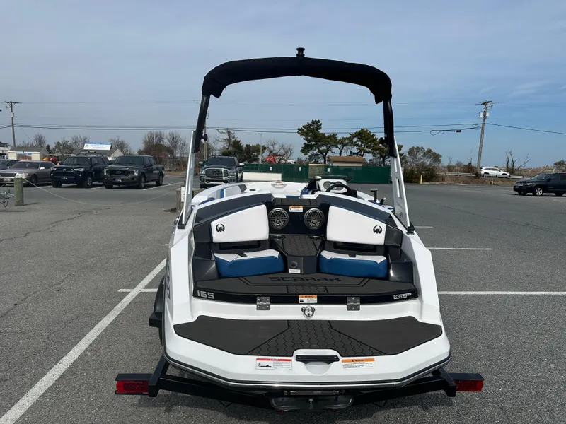 Slide: The Image of 2023 Scarab 165ID boat with black and white seating, parked in a lot. - 7