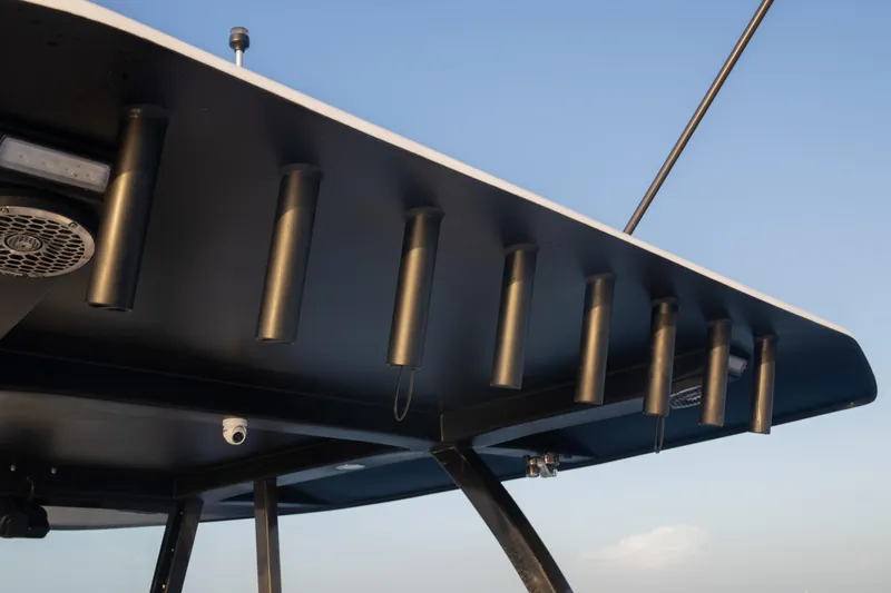 Slide: The Image of 2024 Hammer Yachts 35 T-top with rod holders and speaker, under clear blue sky. - 8