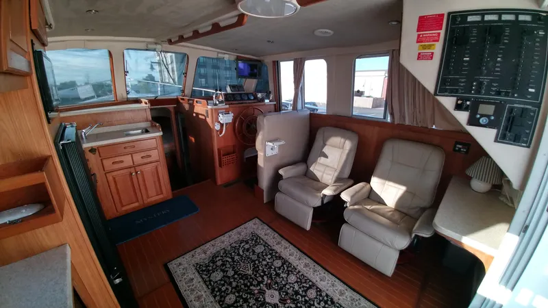 Slide: The Image of 1999 Mainship 350 Trawler interior with helm, seating, and kitchenette. - 13