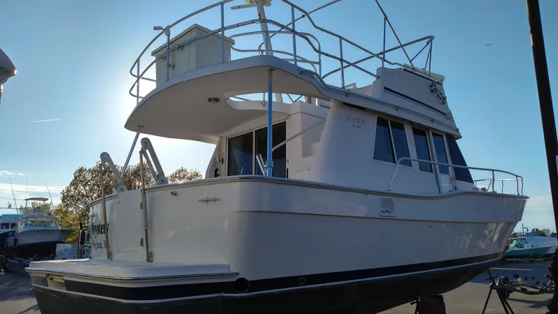Slide: The Image of 1999 Mainship 350 Trawler boat docked, side view with upper deck and railings. - 3