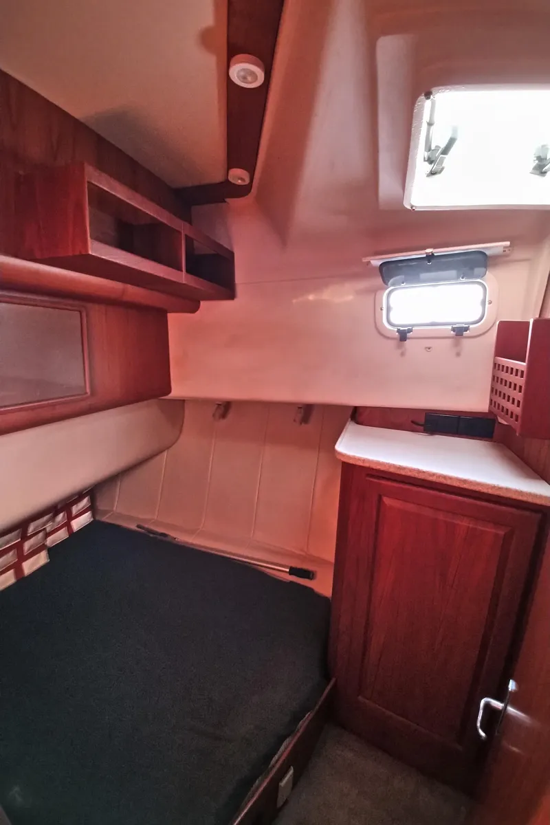 Slide: The Image of 1999 Mainship 350 Trawler cabin interior with bed, wooden cabinets, and porthole window. - 35
