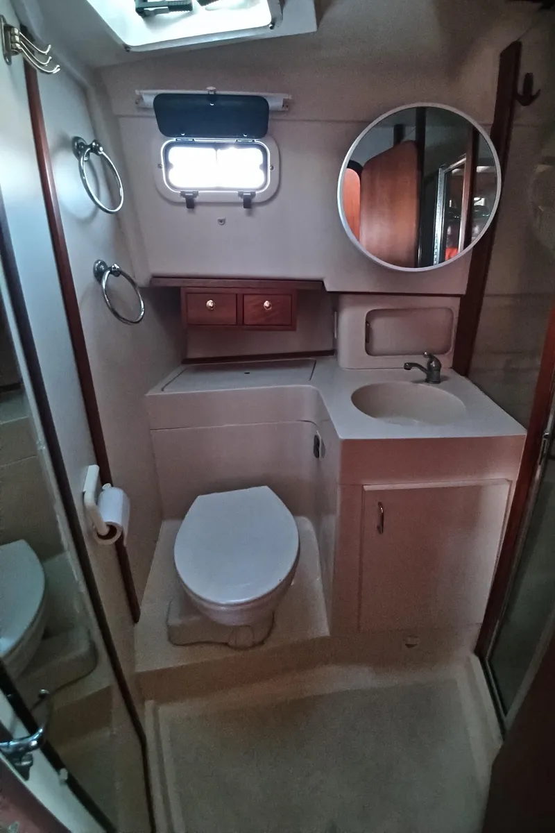 Slide: The Image of 1999 Mainship 350 Trawler bathroom with toilet, sink, mirror, and storage cabinets. - 36