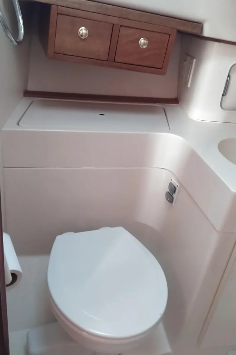 Slide: The Image of 1999 Mainship 350 Trawler bathroom with toilet and wooden storage cabinets. - 37