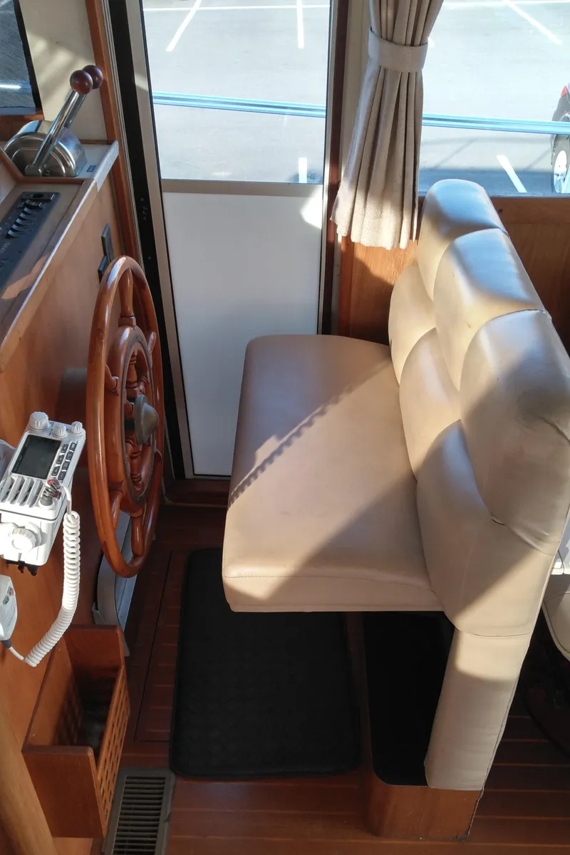Slide: The Image of 1999 Mainship 350 Trawler helm station with wooden steering wheel and cushioned seat. - 48
