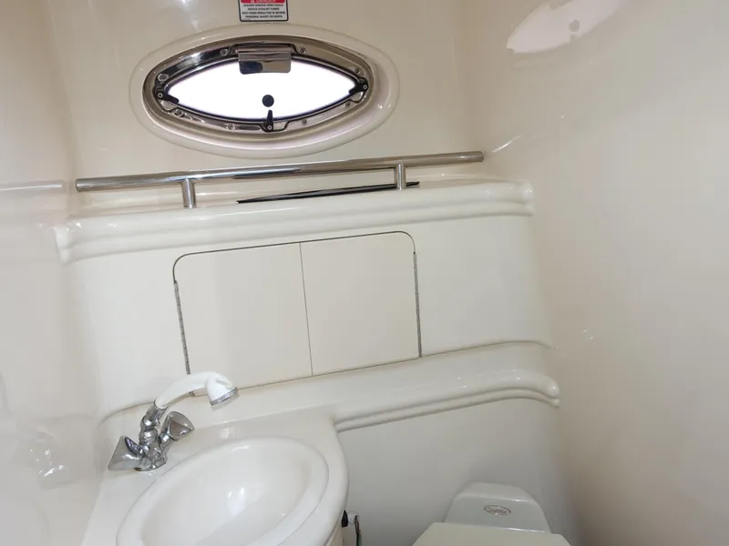 Slide: The Image of 2004 Sea Ray 280 Sundancer bathroom interior with sink and porthole window. - 11