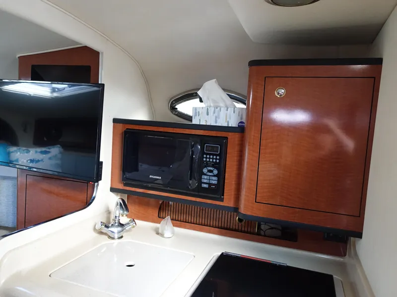 Slide: The Image of 2004 Sea Ray 280 Sundancer cabin with microwave, sink, and wooden cabinetry. - 16