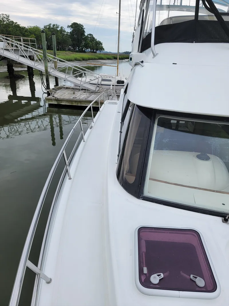 Slide: The Image of 2003 Robertson & Caine Lion 46 yacht docked by a serene waterfront. - 16