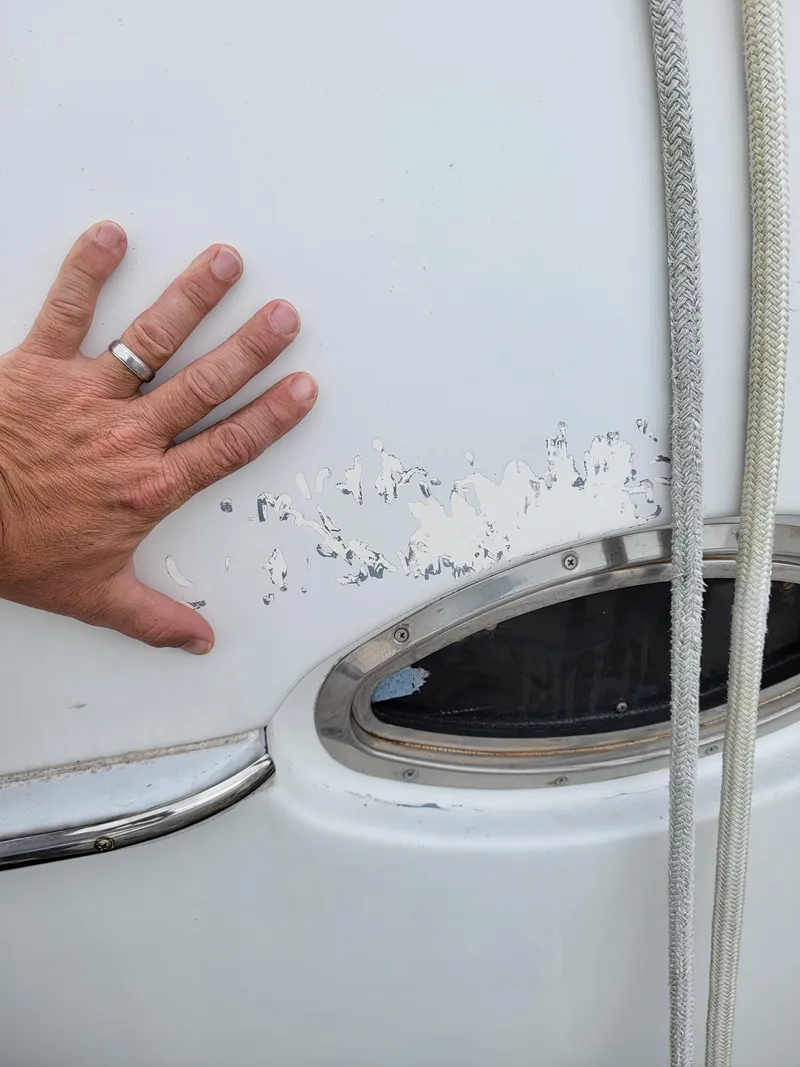 Slide: The Image of Hand touching damaged paint on 2003 Lion Robertson & Caine Lion 46 boat exterior. - 47