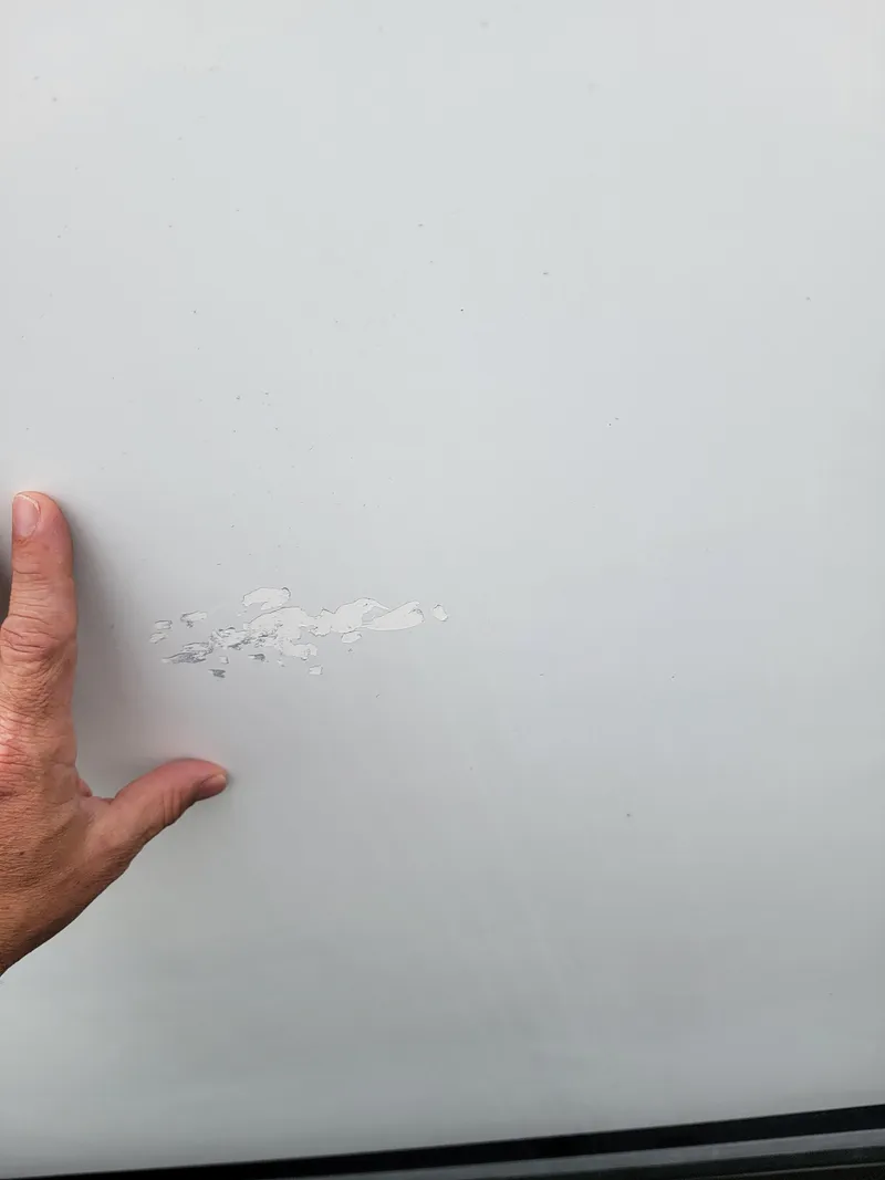 Slide: The Image of Close-up of a hand near paint damage on a 2003 Robertson & Caine Lion 46. - 49