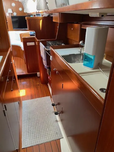 Slide: The Image of 2001 Beneteau Oceanis 44 CC yacht interior with wooden cabinetry and compact kitchen area. - 13