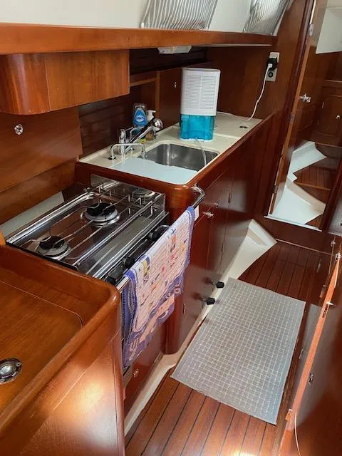 Slide: The Image of 2001 Beneteau Oceanis 44 CC yacht kitchen with stove, sink, and wooden cabinetry. - 14
