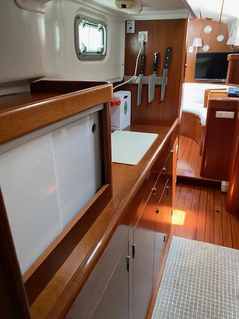 Slide: The Image of Interior of 2001 Beneteau Oceanis 44 CC yacht, featuring a sleek kitchen area with wooden cabinetry. - 15
