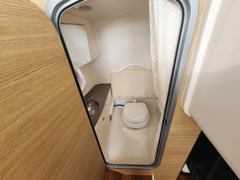 Slide: The Image of 2012 Chaparral 327 SSX boat bathroom with toilet, sink, and shower curtain. - 13