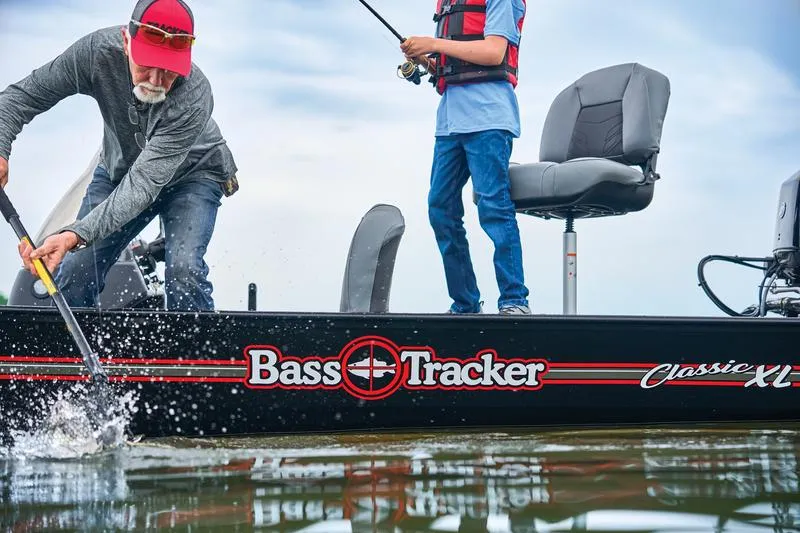 Slide: The Image of 2024 Tracker Bass Tracker Classic XL boat with two people fishing on a lake. - 2