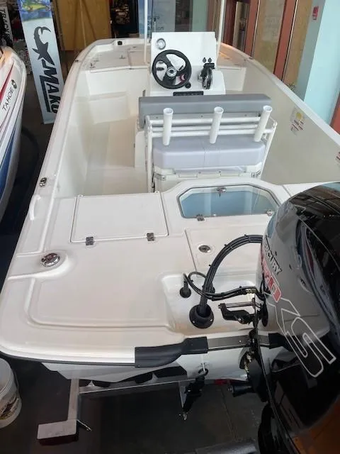Slide: The Image of 2024 Mako Pro Skiff 19 CC boat interior with steering console and outboard motor. - 2