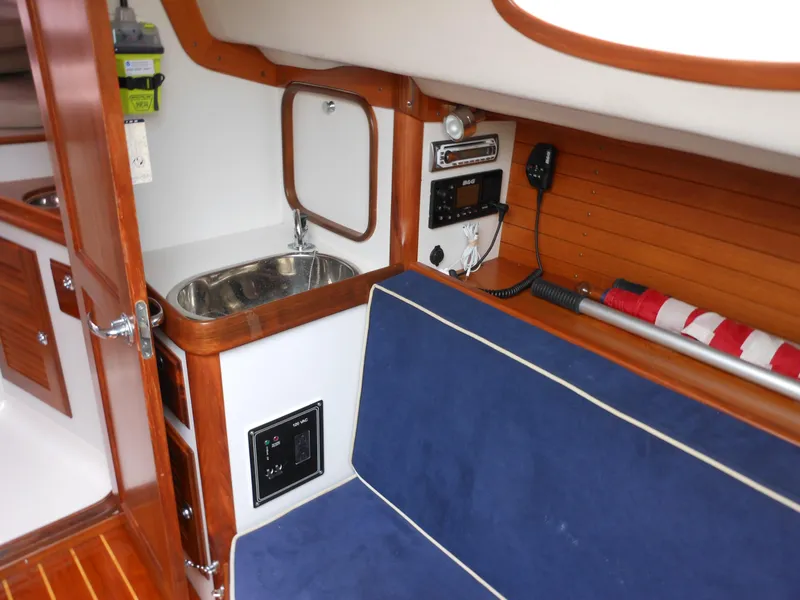 Slide: The Image of 2009 Alerion Express 33 interior with sink, blue seating, and wooden accents. - 14