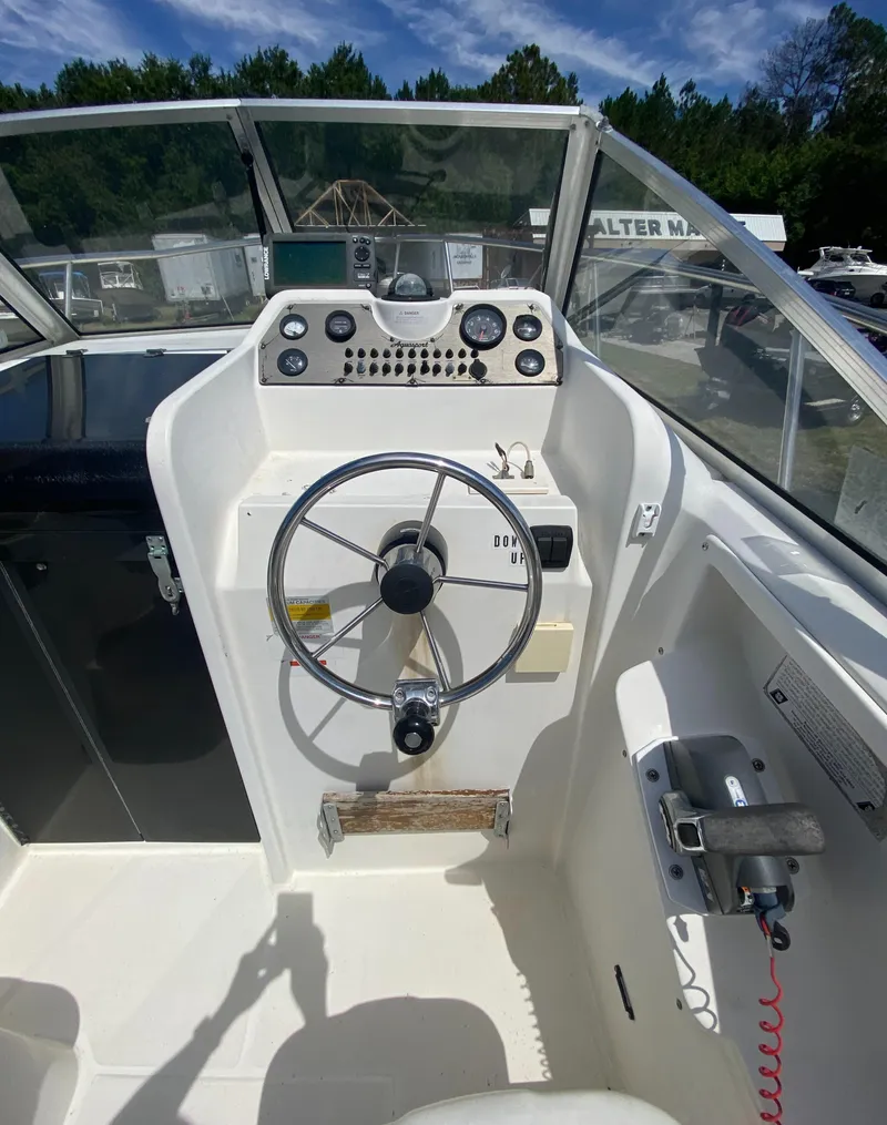 Slide: The Image of 1999 Aquasport 245 Explorer boat helm with steering wheel and control panel. - 15