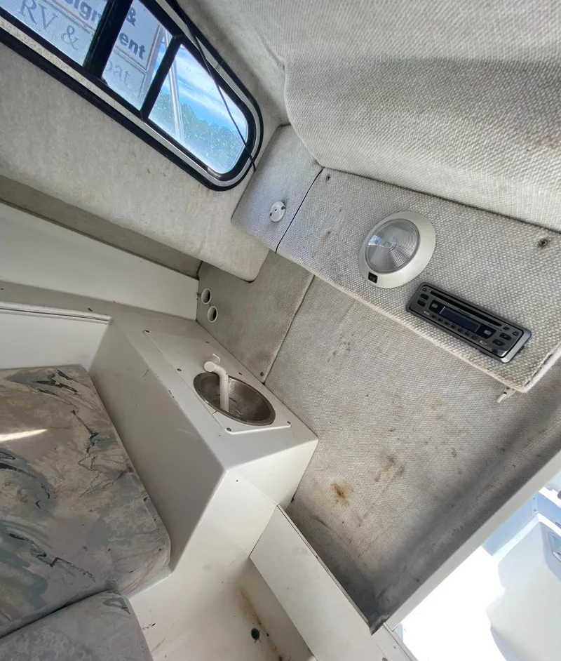 Slide: The Image of 1999 Aquasport 245 Explorer cabin interior with seating and storage. - 17