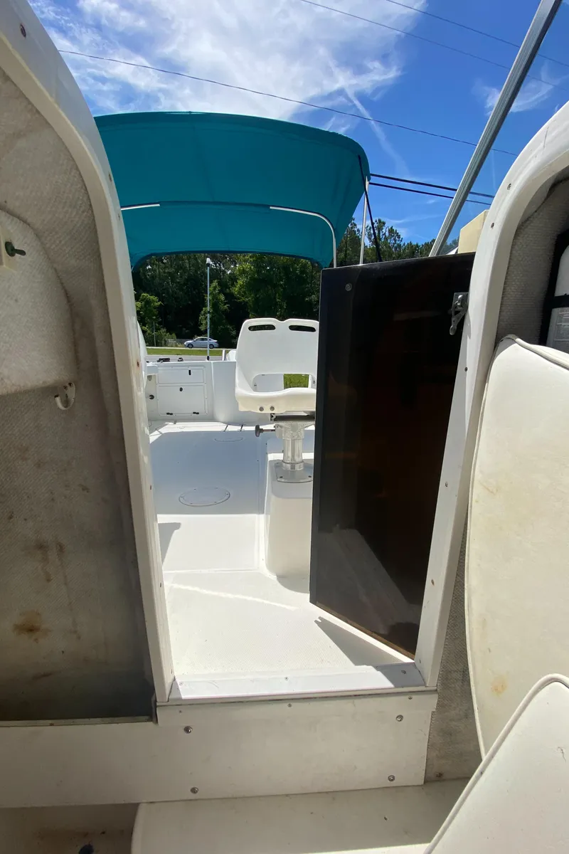 Slide: The Image of 1999 Aquasport 245 Explorer boat interior with blue canopy and white seating. - 18