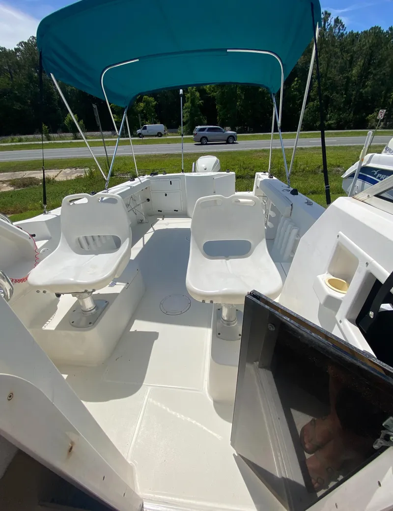 Slide: The Image of 1999 Aquasport 245 Explorer boat interior with seating and blue canopy. - 19