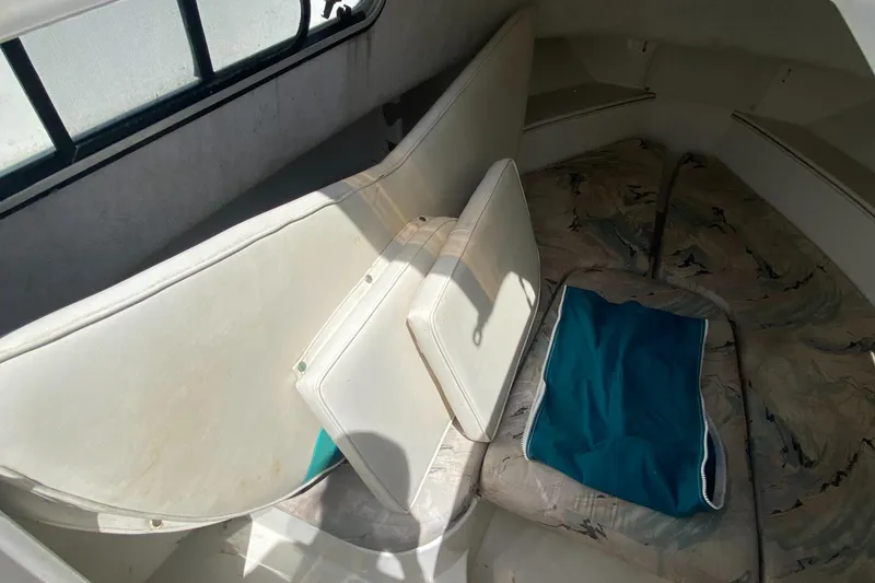 Slide: The Image of 1999 Aquasport 245 Explorer cabin interior with cushions and window. - 20