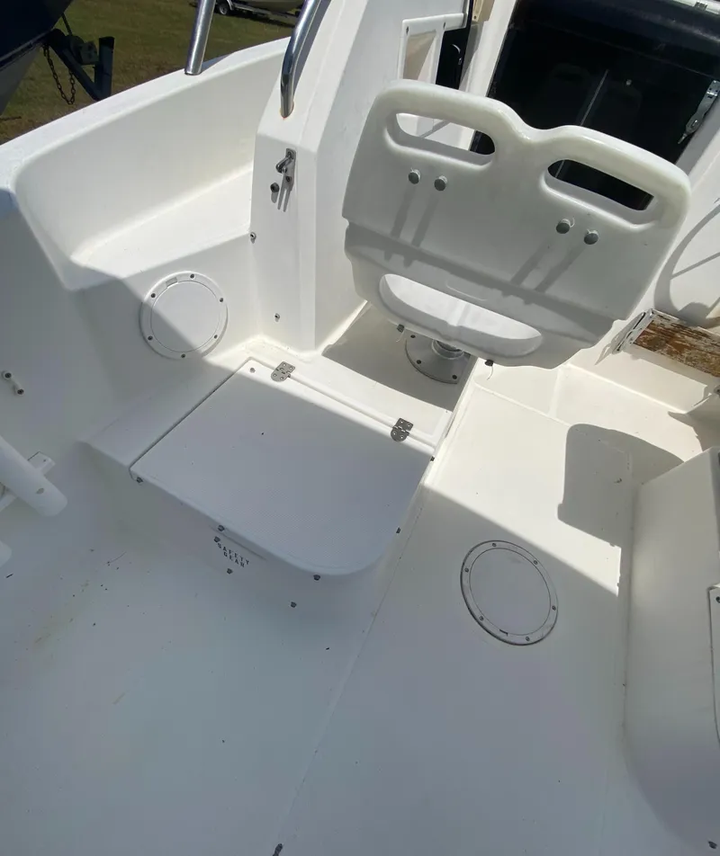 Slide: The Image of 1999 Aquasport 245 Explorer boat interior with white seating and storage compartments. - 25