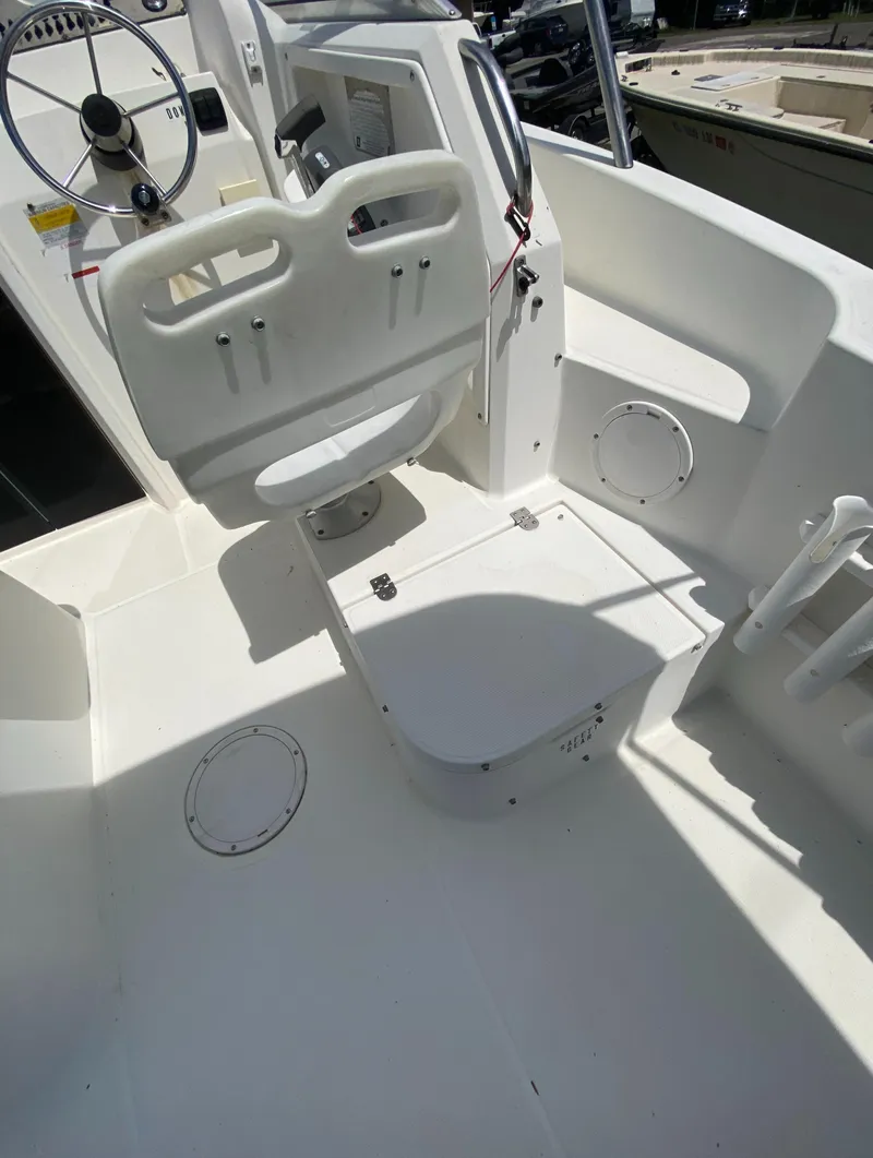 Slide: The Image of 1999 Aquasport 245 Explorer boat cockpit with captain's chair and storage compartments. - 26