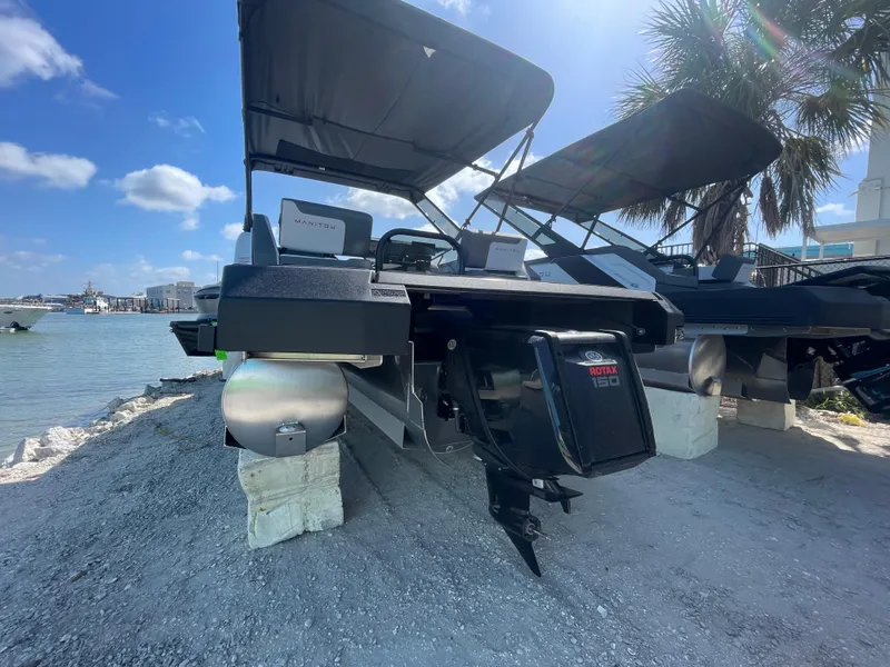 Slide: The Image of 2024 Manitou Cruise pontoon boat docked by the shore under a clear blue sky. - 13