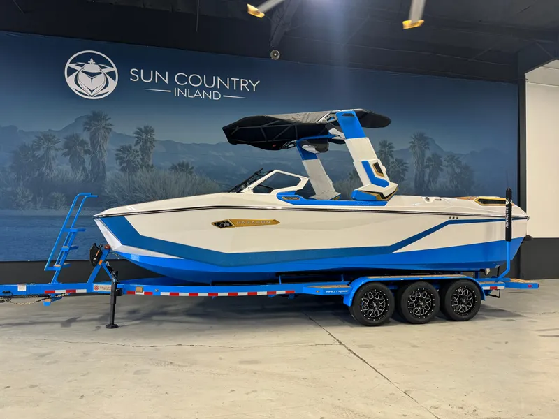 Slide: The Image of 2025 Nautique Super Air Nautique G25 Paragon boat in showroom, blue and white design. - 2