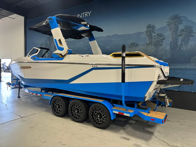 Slide: The Image of 2025 Nautique Super Air Nautique G25 Paragon boat in showroom, blue and white design on trailer. - 3