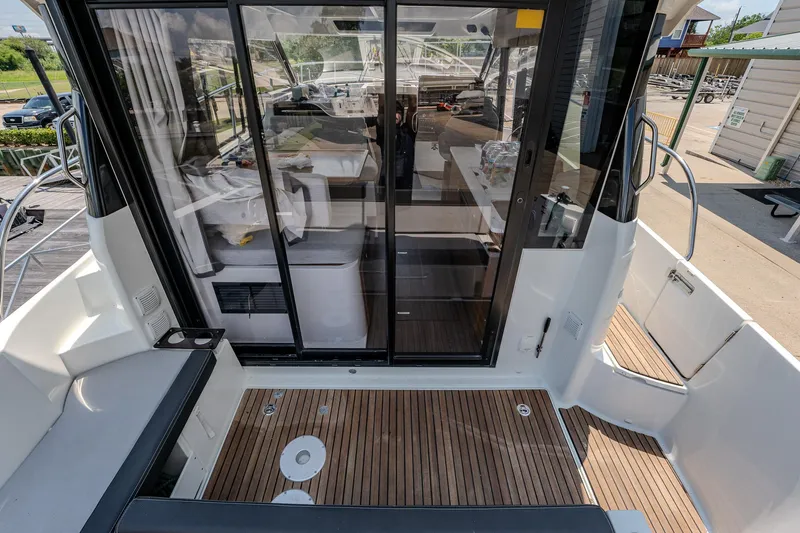 Slide: The Image of 2021 Jeanneau NC Weekender 1095 boat interior with sliding glass doors and wooden deck. - 14