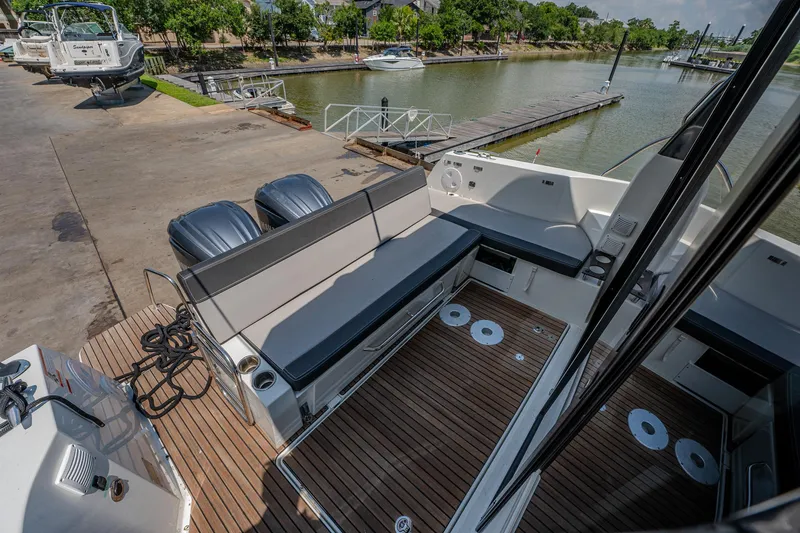 Slide: The Image of 2021 Jeanneau NC Weekender 1095 boat with spacious deck and seating at a marina. - 15