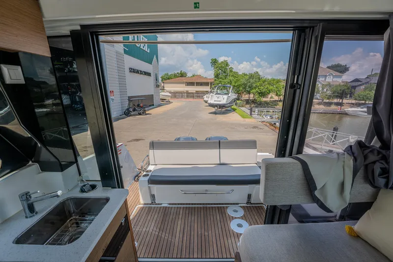 Slide: The Image of Interior view of 2021 Jeanneau NC Weekender 1095, showing seating and dockside scenery. - 17