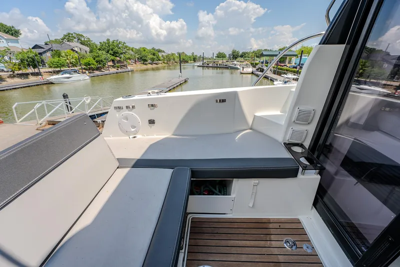 Slide: The Image of 2021 Jeanneau NC Weekender 1095 boat deck with seating, docked by a scenic waterfront. - 20