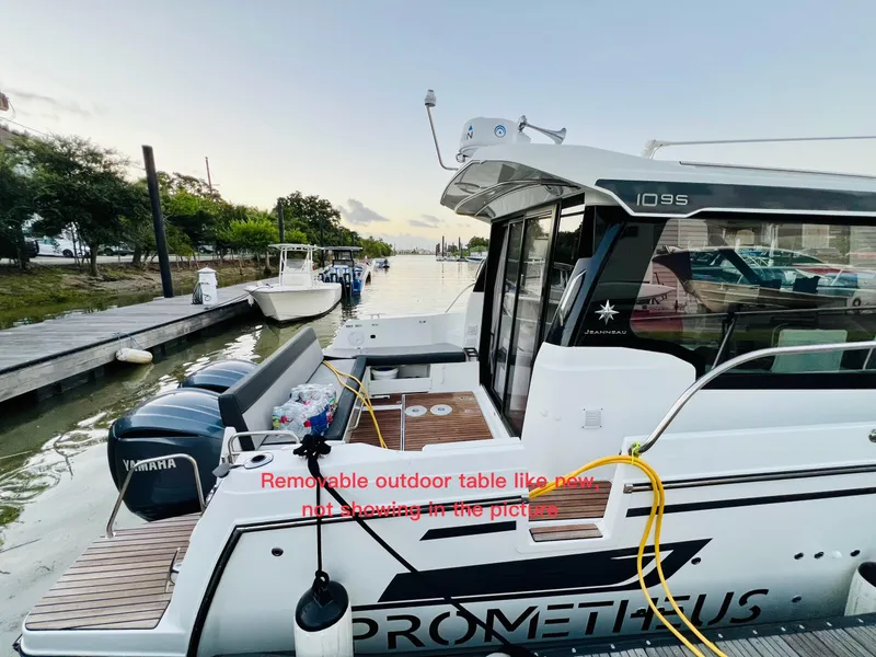 Slide: The Image of 2021 Jeanneau NC Weekender 1095 docked, showcasing the spacious deck and Yamaha outboard motor. - 8