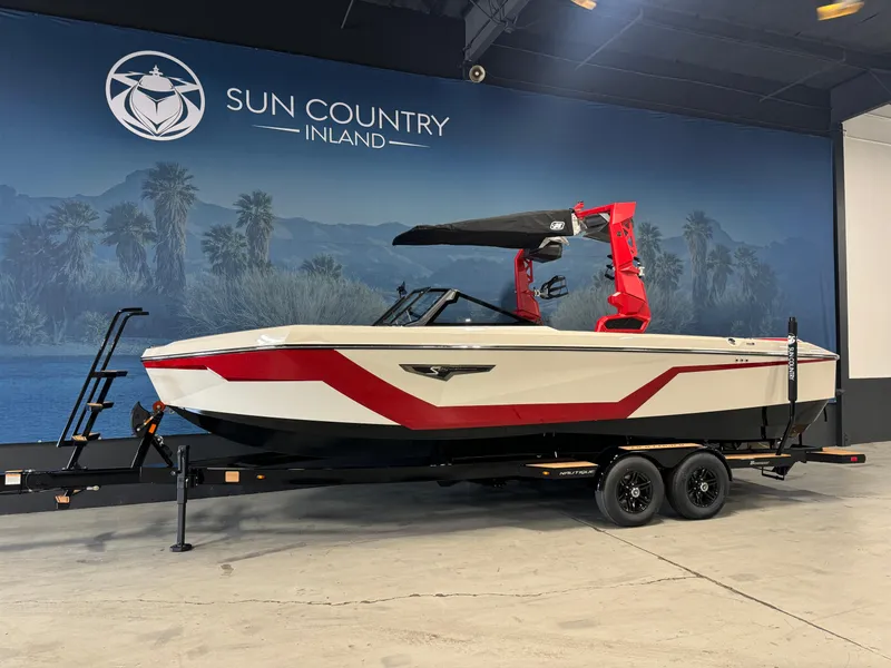 Slide: The Image of 2025 Nautique Super Air S25 boat with red accents on a trailer at Sun Country Inland showroom. - 2