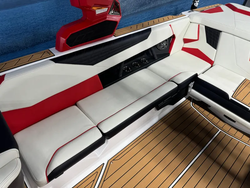 Slide: The Image of 2025 Nautique Super Air S25 interior with red, white, and black seating on teak flooring. - 8