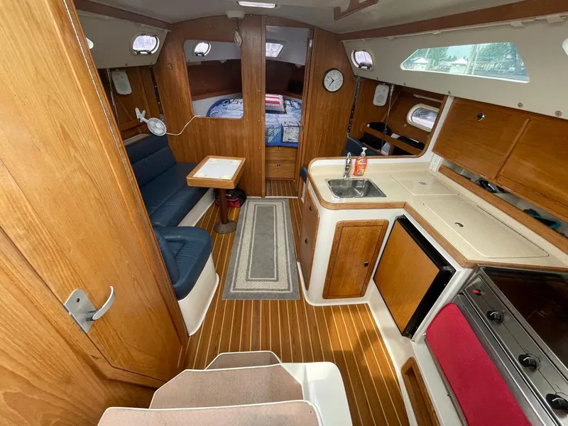 Slide: The Image of Interior of 2000 Catalina 310 sailboat with wood finish, kitchenette, and seating area. - 25