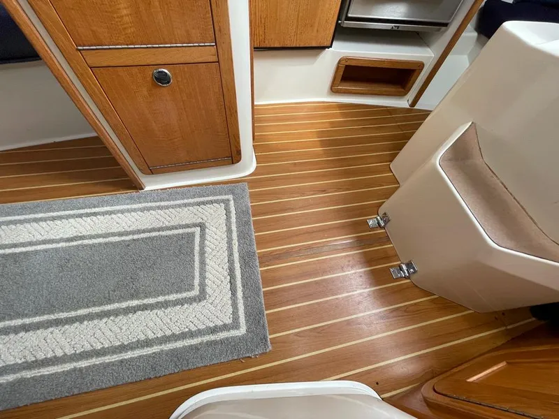 Slide: The Image of Interior of a 2000 Catalina 310 sailboat with wood flooring and a gray rug. - 28