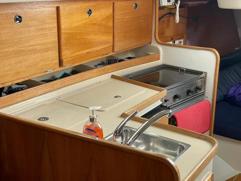Slide: The Image of Interior of 2000 Catalina 310 sailboat kitchen with sink, stove, and wooden cabinets. - 36