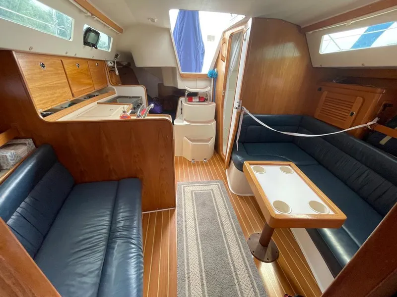 Slide: The Image of Interior of a 2000 Catalina 310 sailboat with wood finish and blue seating. - 38