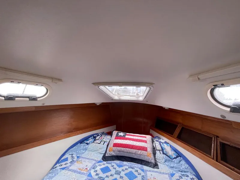 Slide: The Image of Cozy cabin interior of a 2000 Catalina 310 sailboat with quilted bedding and porthole windows. - 39