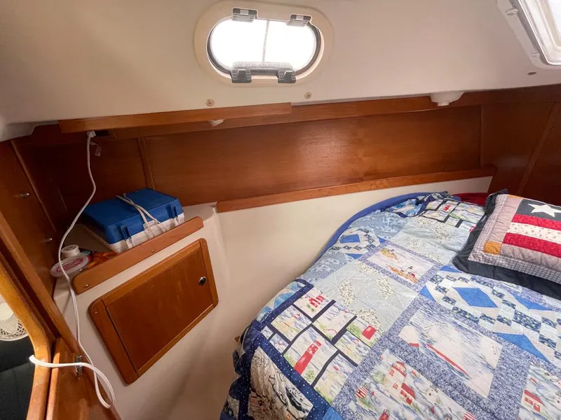 Slide: The Image of Cozy cabin interior of a 2000 Catalina 310 sailboat with quilted bedding and wooden storage. - 40