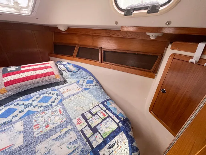 Slide: The Image of Cozy cabin interior of 2000 Catalina 310 sailboat with quilted bedding and wooden accents. - 41