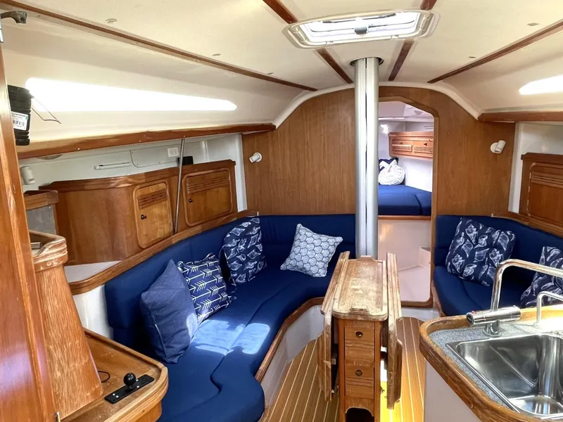 Slide: The Image of Interior of 2001 C&C 110 sailboat with blue seating, wooden cabinetry, and cozy decor. - 11