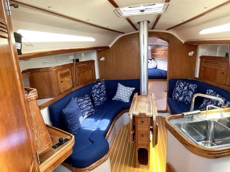 Slide: The Image of Interior of a 2001 C&C 110 sailboat with blue seating, wooden cabinetry, and a compact kitchen. - 12