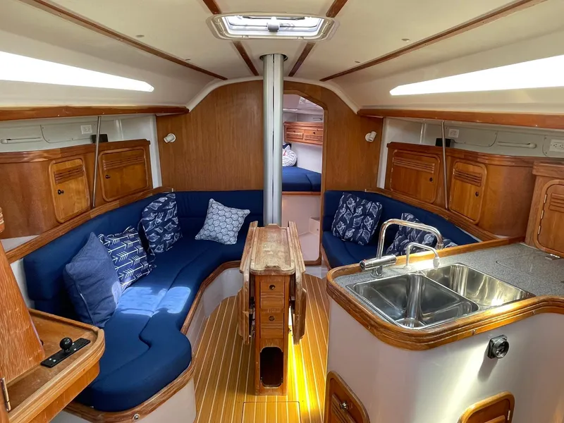 Slide: The Image of Interior of 2001 C&C 110 sailboat with blue seating, wooden cabinetry, and kitchenette. - 14